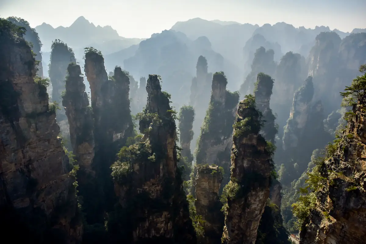 Mist drifting between tall sandstone pillars in a dramatic Chinese mountain landscape